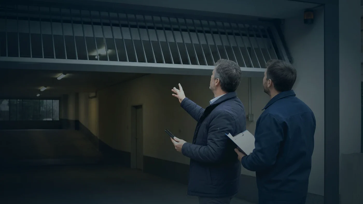 Hausverwaltung und Servicetechniker besprechen in einer Tiefgarage in Wien Niederösterreich die Verwaltung von Handsendern und Zutrittssystemen an einem Garagentor, realistische Technikfotografie ohne Logos